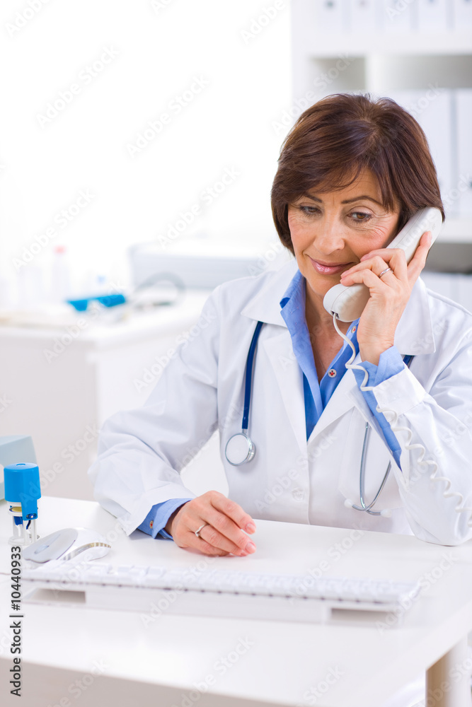 Senior female doctor calling on phone, smiling. Senior female doctor calling on phone, smiling.