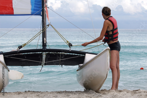 woman pulling sailboat on the caribbean beach photo