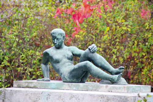 Statue de femme en bronze allongée sur un socle de pierre