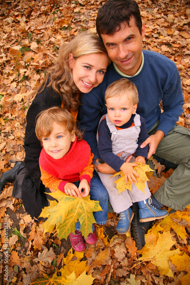 Family of four with yellow maple leaves in wood in autumn. Family of four with yellow maple leaves in wood in autumn.