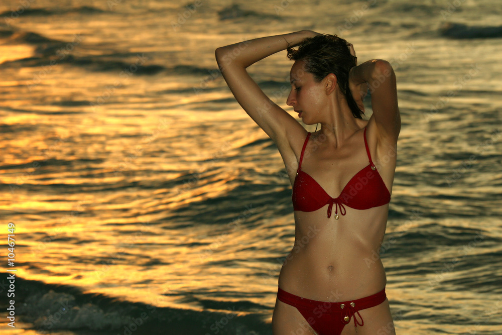 Woman in red bikinis on the beach by sunset