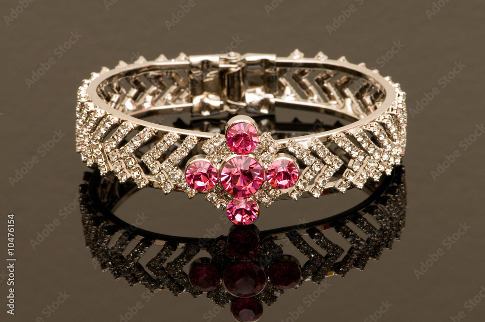 Obraz premium Bracelet with red stones on reflective background