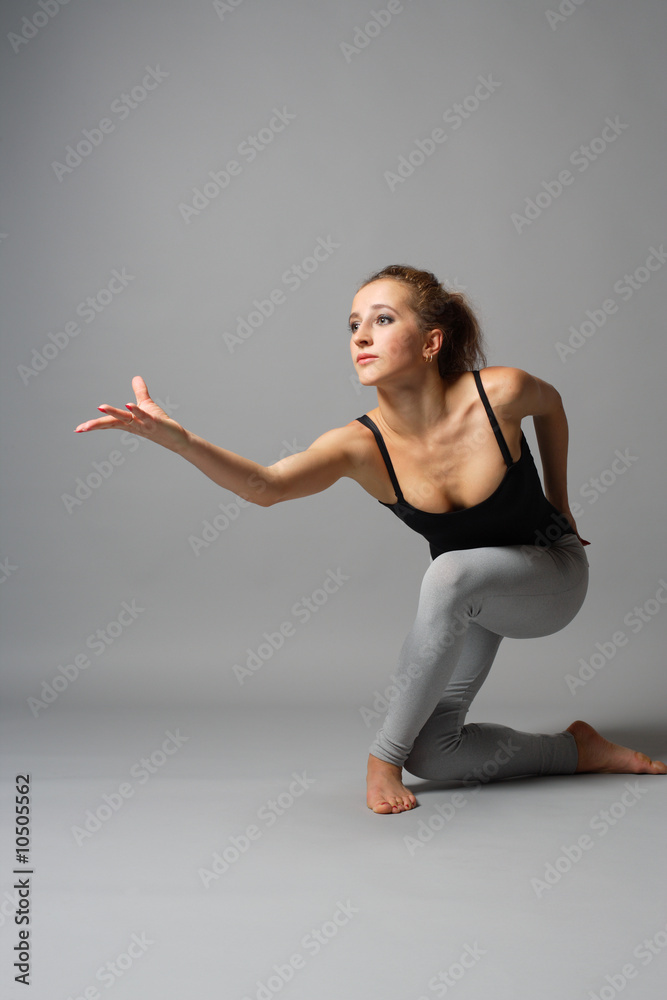 young and beautiful ballet dancer posing on grey
