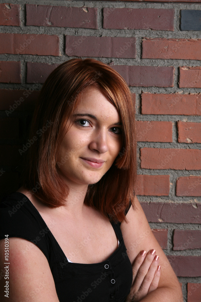 pretty auburn haired teenage girl in front of a brick wall pretty auburn haired teenage girl in front of a brick wall
