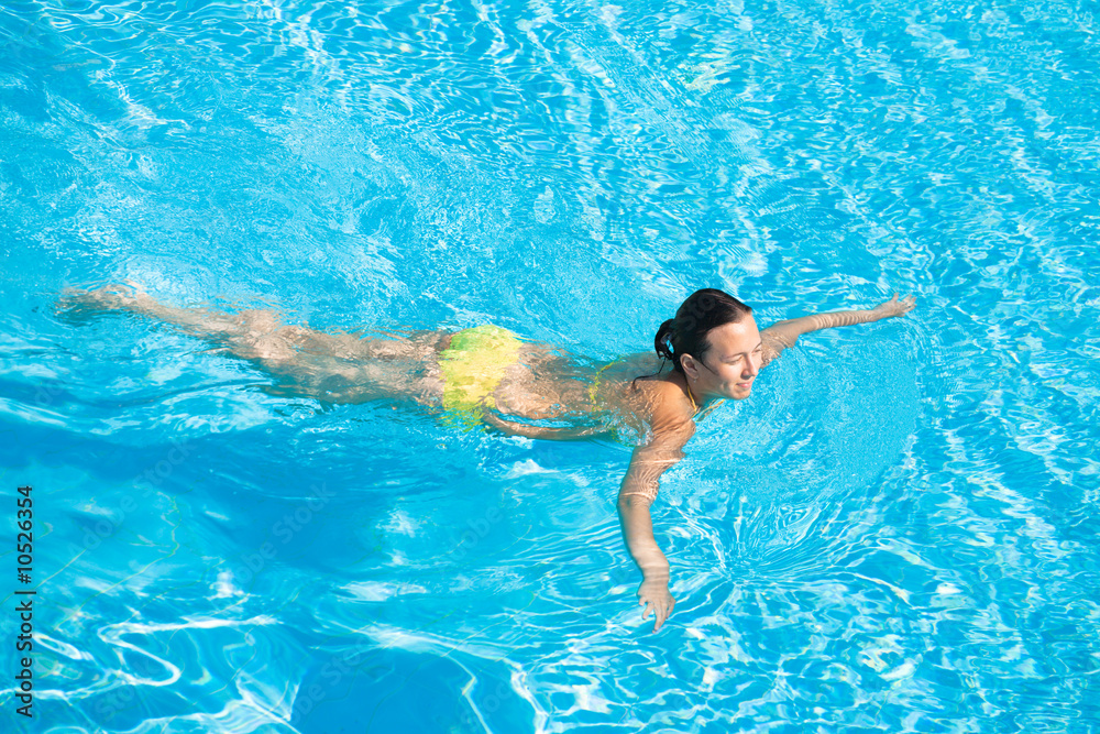 Young beautiful caucasian woman in bikini swimming in pool