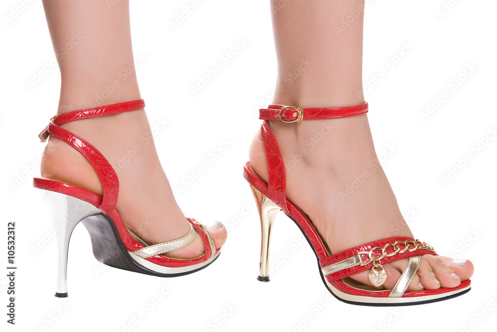 Slim female legs in red sandals isolated on a white background Slim female legs in red sandals isolated on a white background