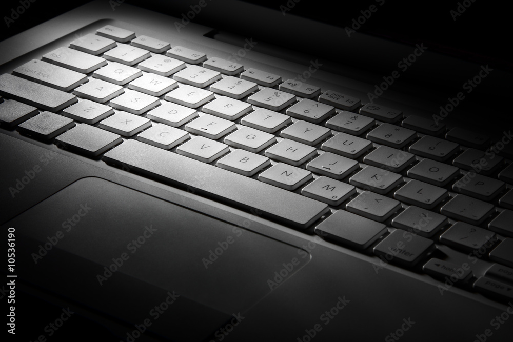 White laptop keyboard in light beam.