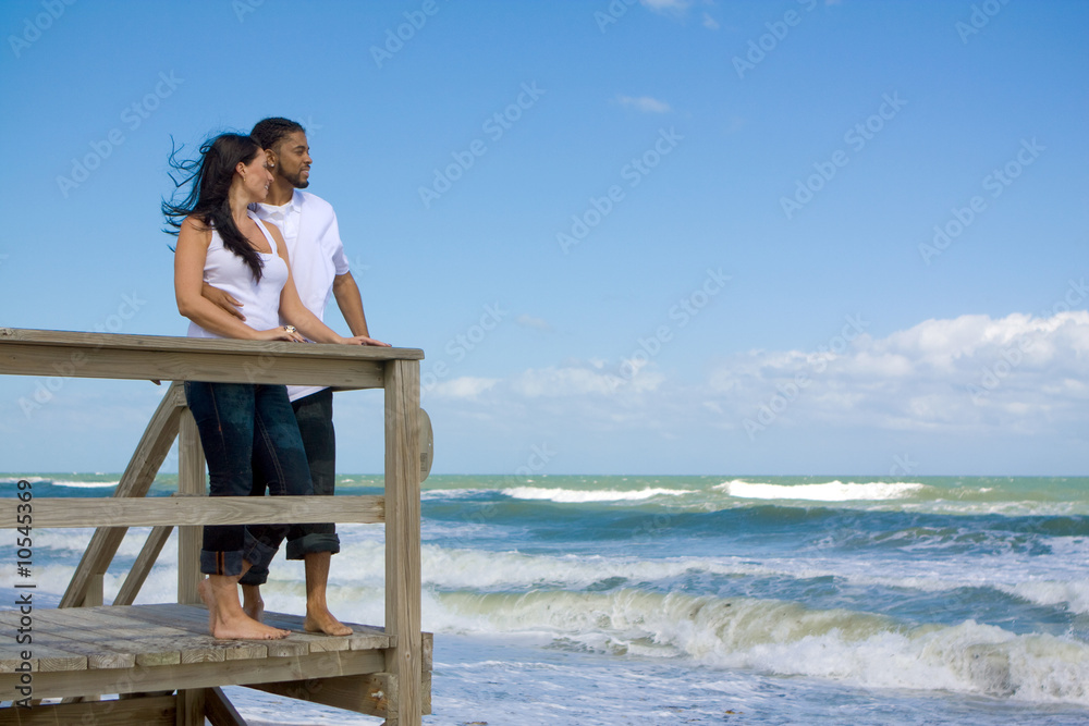 Couple standing at the beach, looking at the ocean