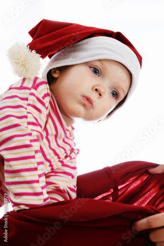 An image of happy baby in red hat looking into christmas bag