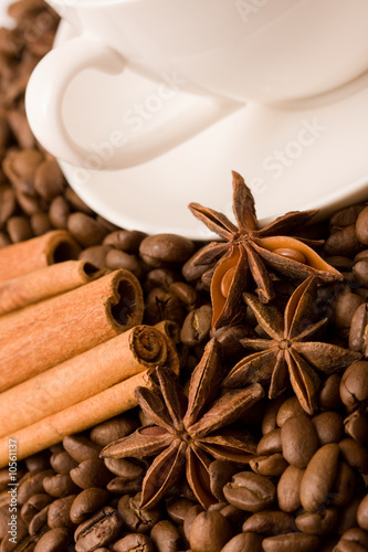 cup of coffee with whole beans, cinnamon and anise