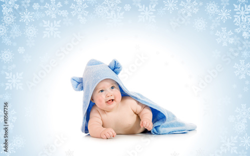 Small smiling baby with a towel on snowy background