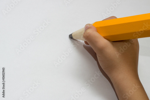 Child hand with big orange pencil