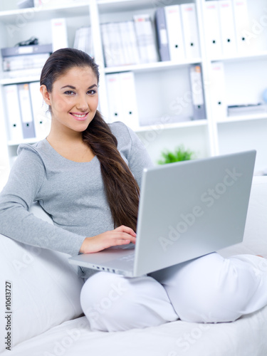 Smiled Young woman sitting on couch and working on laptop