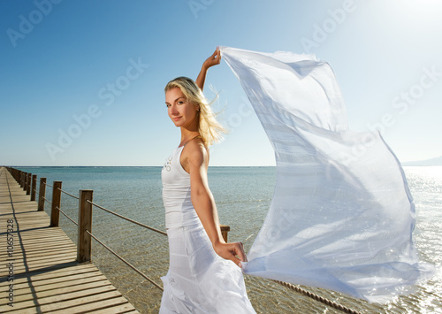 Blond woman with white shawl relaxing near the sea