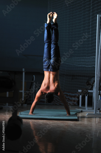 Canvas Print young man performing handstand in fitness studio