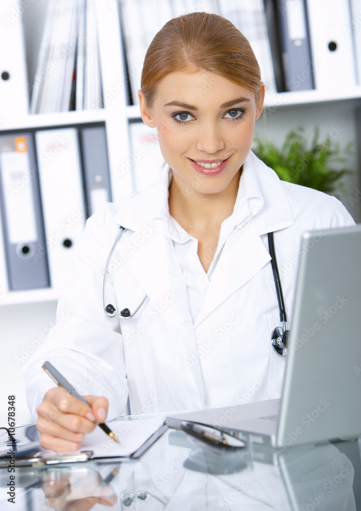 Smiling female doctor writing notes in clipboard