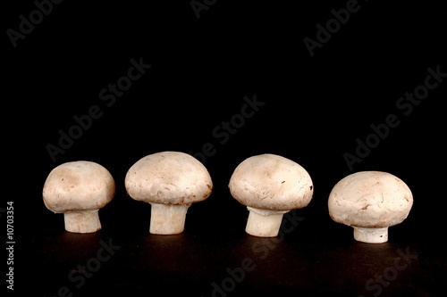 Four fresh cuted champignons isolated on black background.