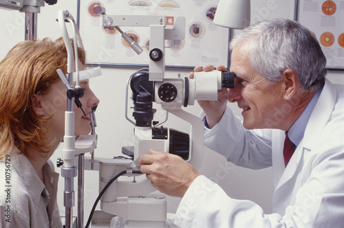 optometrist with patient, giving an eye examination photo
