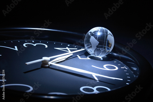 Litte glassy globe on dark background with watch photo