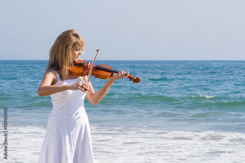 young caucasian woman play violin on beach