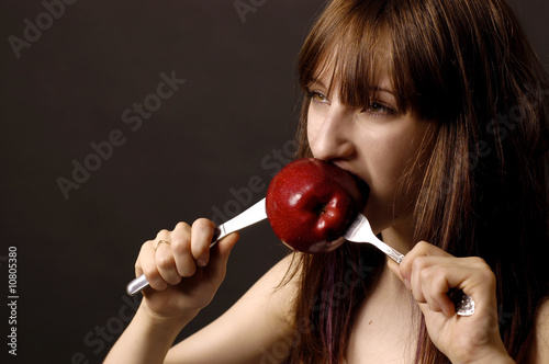 Beatiful girl is eating the red apple with appetite photo