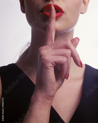 a woman holds her finger to her lips to say ssshhhh.