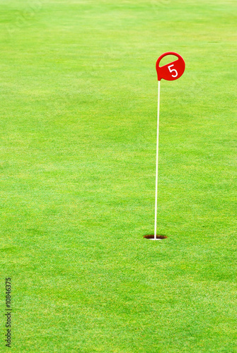 Golf practice putting hole marked with a red sign