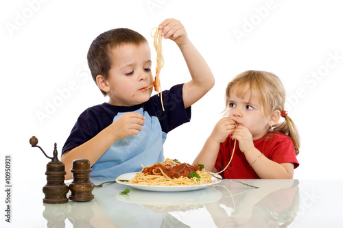 Two kids eating pasta with their hands