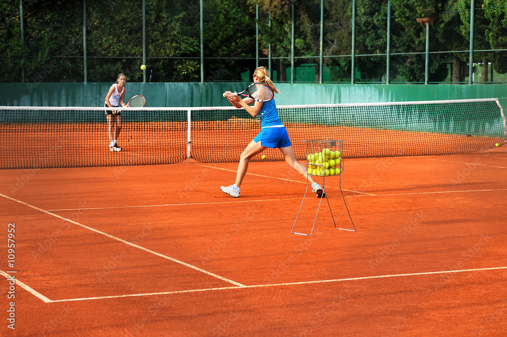 Two young women playing tennis outdoors on Two young womwn playi