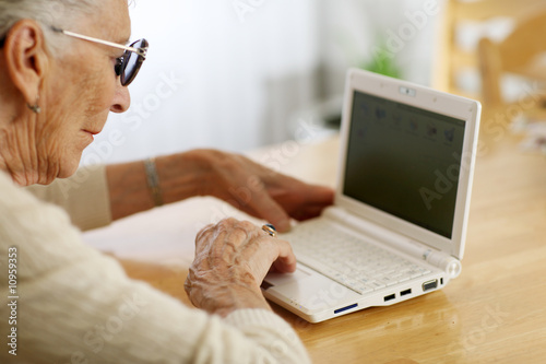 Elderly woman typing on laptop computer photo