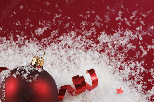 Beautiful red Christmas bauble with star, ribbons and fake snow photo