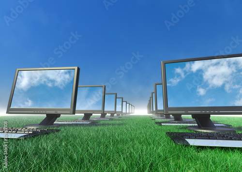 A row of computers in a field of grass.