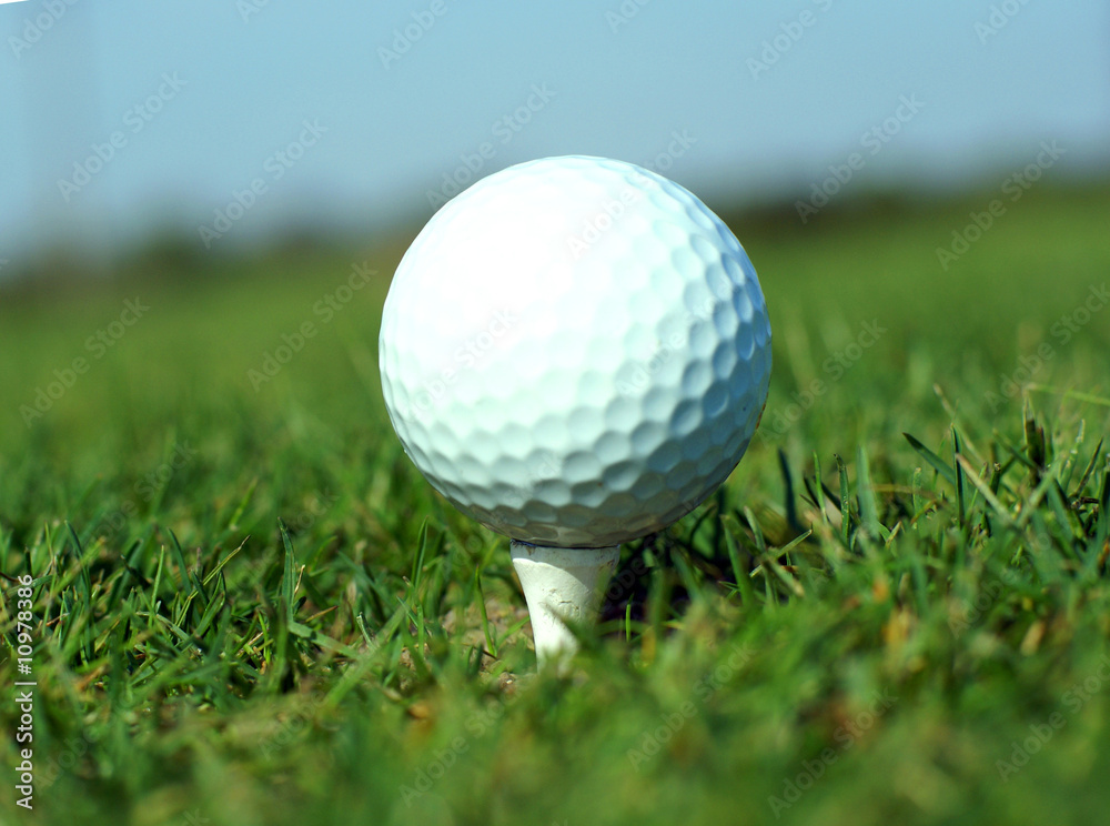 Golf ball in tall green grass set against blue sky Golf ball in tall green grass set against blue sky