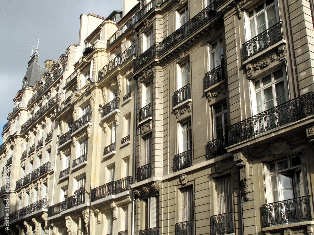 Rue de Paris avec immeubles en pierre.