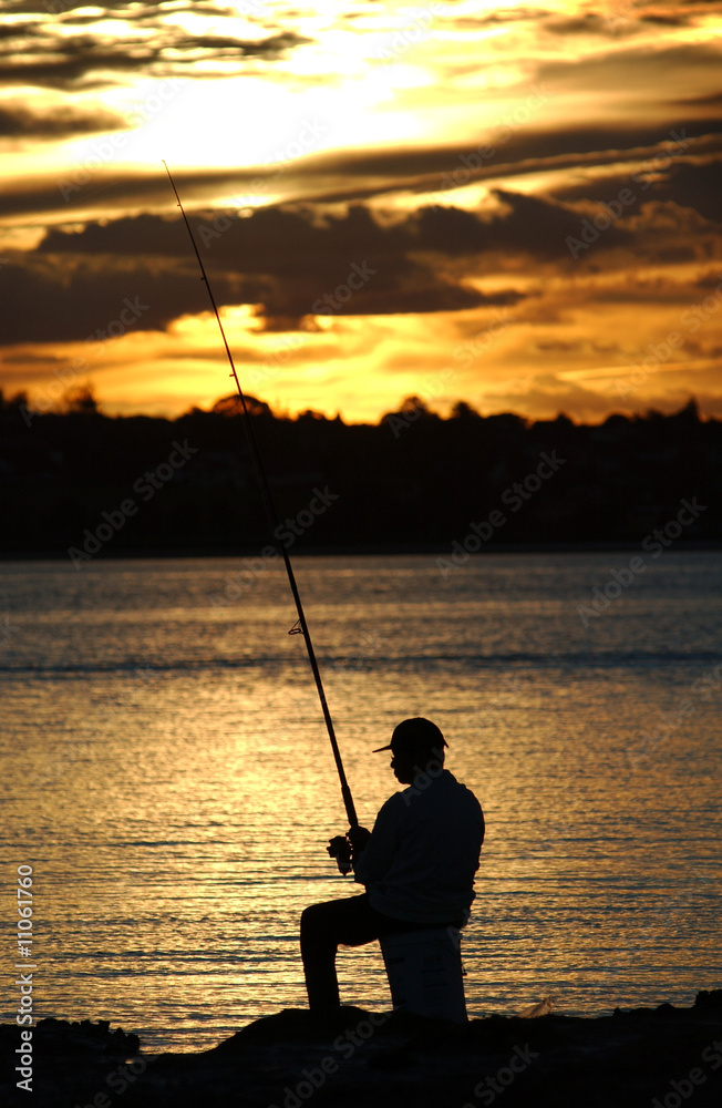 A fisherman on the rocks at dusk