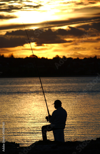 A fisherman on the rocks at dusk