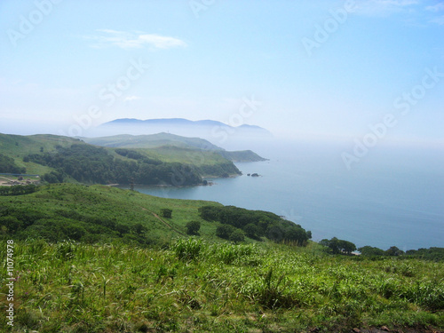 Blue bay in sunny day, distant island in the fog