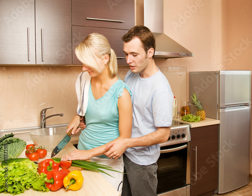 Young couple making vegetable salad in the kitchen