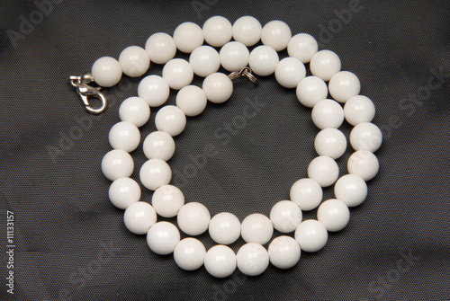 Necklace from a white stone, on a black pattern, spiral.