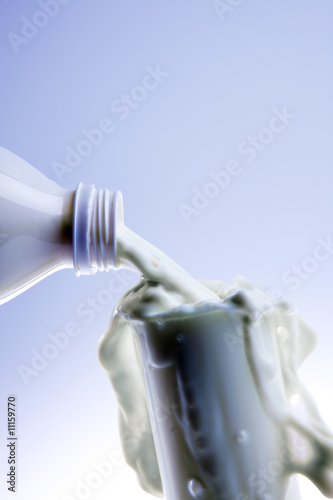 pouring creamy fresh milk in a transparent glass photo