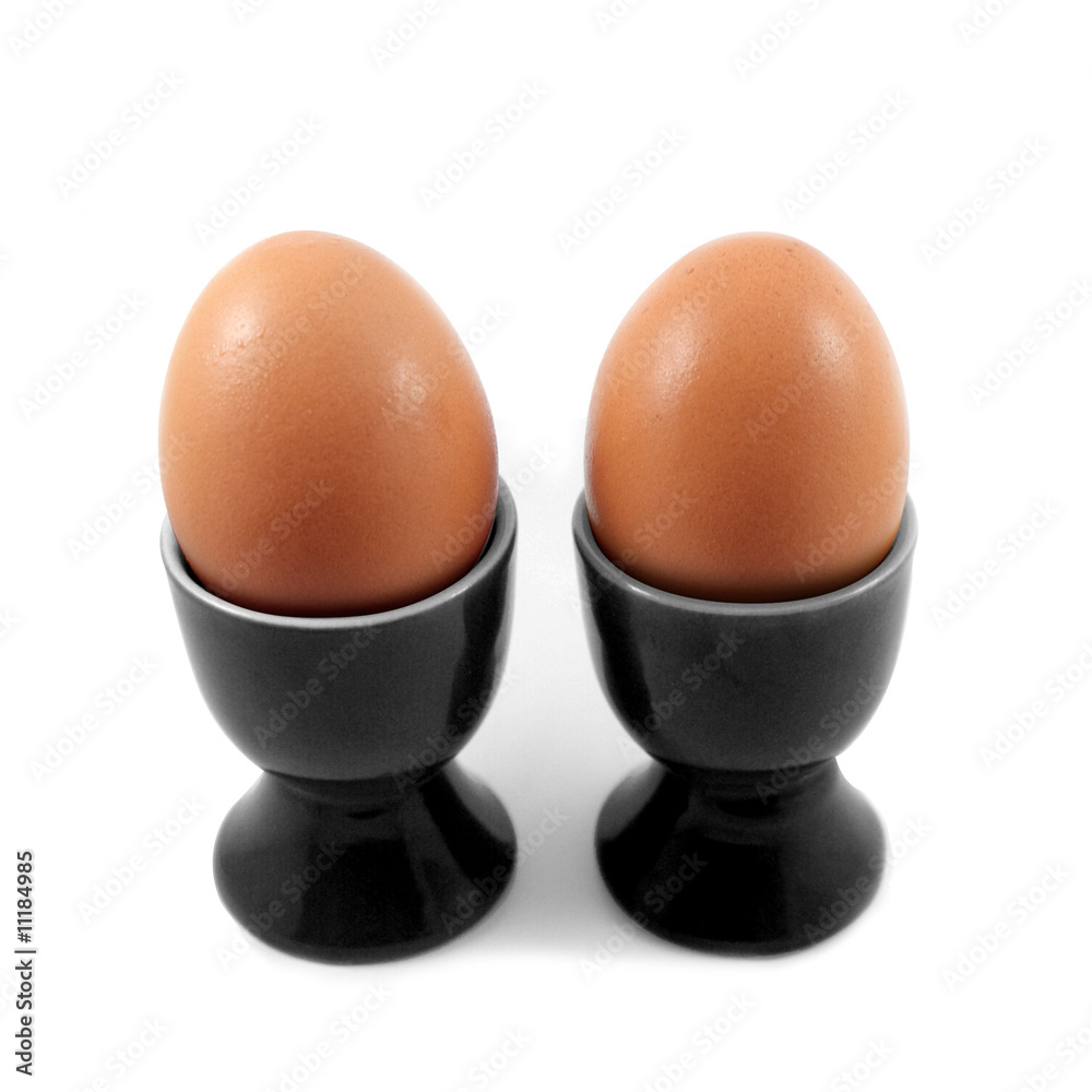 Deux oeufs dans coquetiers noirs isolés