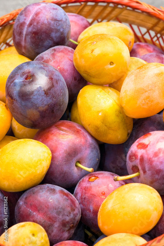 Basket of fruits, yellow and purple plum.