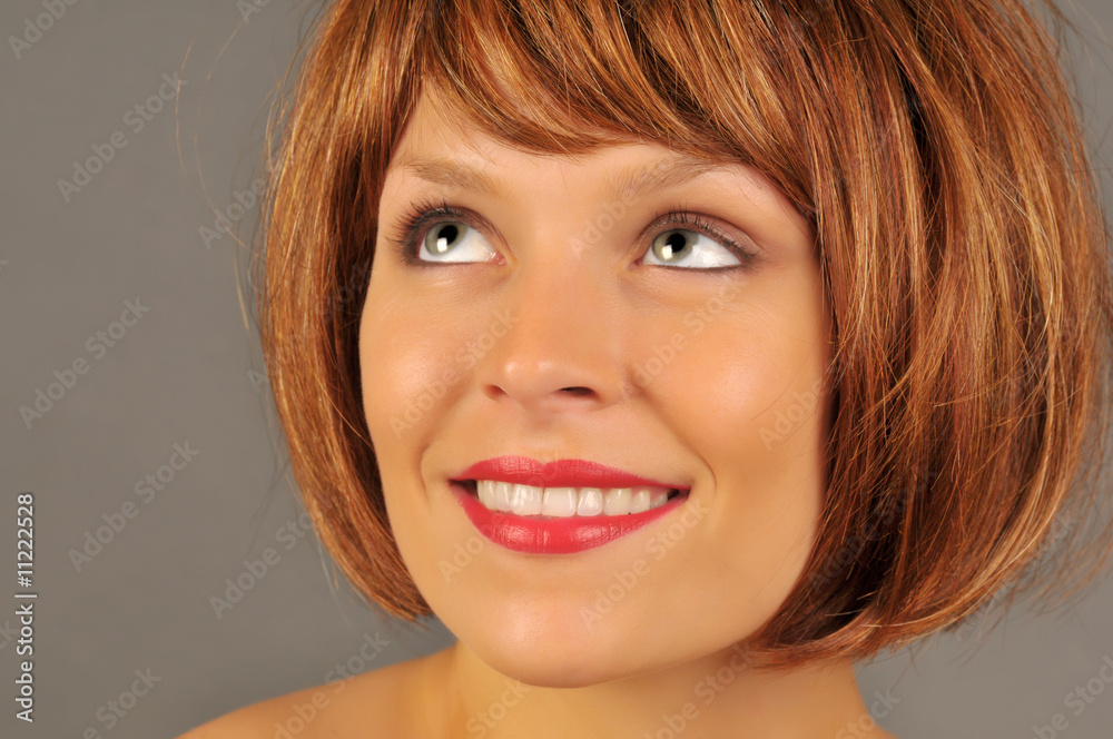Naklejka premium Beautiful woman with red hair smiling and looking upward.