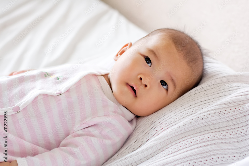Baby lying in bed, curious expression on her face Baby lying in bed, curious expression on her face