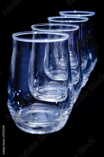four empty glasses in a diagonal row on black - vertical