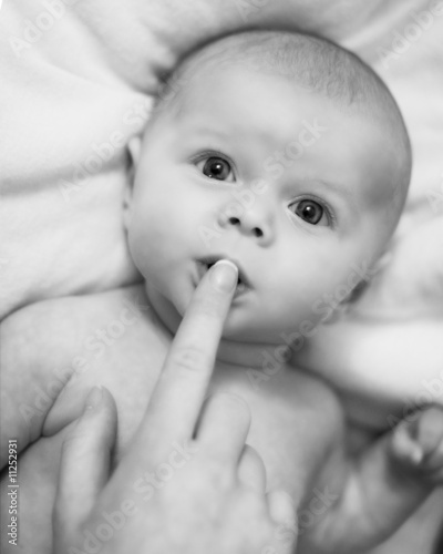 Baby with mother's finger touching the mouth