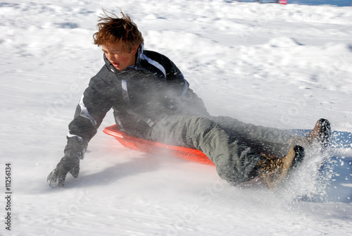 Boy Braking While Sledding Down the Hill