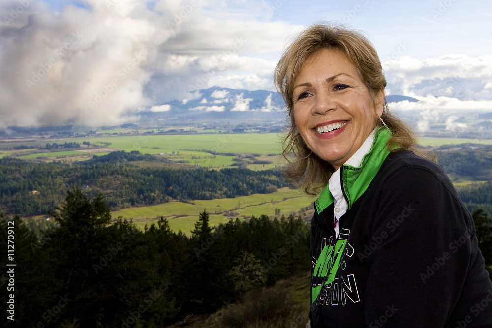 Naklejka premium Happy Mature Woman sitting on a mountain top