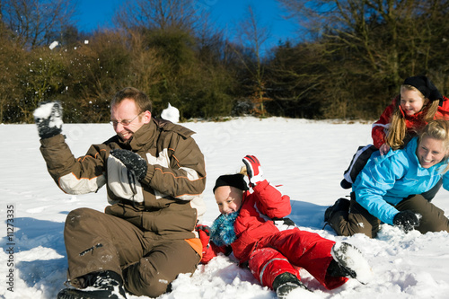 Familie tobt im Winter bei einer Schneeballschlacht