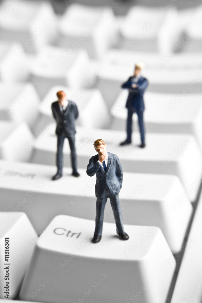 Businessman figurines placed on computer keyboard Businessman figurines placed on computer keyboard